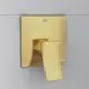 Goldfarbene Brausearmatur von Ideal Standard mit rechteckigem Bedienhebel, montiert an einer hellen Wand.